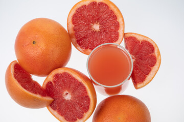Juicy grapefruit with glass of freshly squeezed juice on white