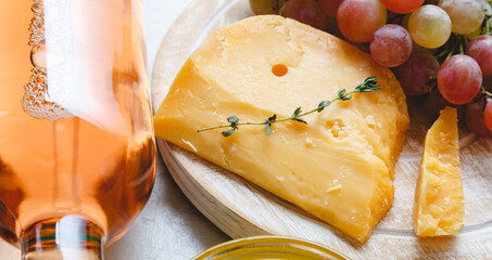 Aged dutch gouda cheese on cheeseboard with cumin herbs on table. Cheddar cheese with grapes, pink wine, honey. Wine cheese snacks for a romantic dinner. Long web banner