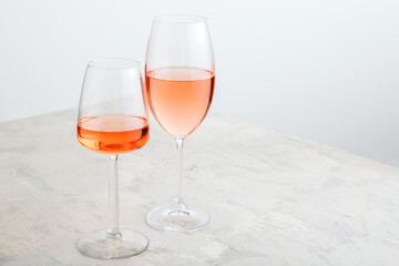 Rose wine in different types of glasses on light concrete background. Minimal Wine composition on white table with copy space.