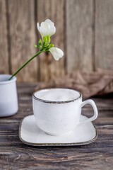 Coffee cappuccino and white freesia flower on a wooden background