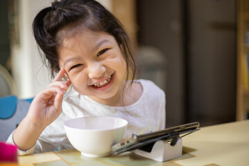 Happy asian girl eating with smartphone at home. New normal. Social distancing. stay home