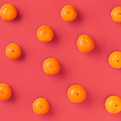 Fruit pattern of fresh orange tangerine or mandarin over living coral background. Flat lay, top view. Pop art design, creative summer concept. Citrus in minimal style..