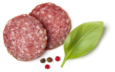 Slices of salami isolated over white background closeup. Sausage and basil leaves top view..