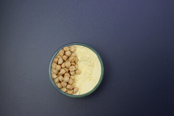 Chickpeas and chickpeas flour in a round glass bowl on a gray background. Pea flour. 