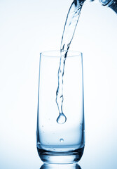 water pouring into glass over blue background.