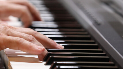 Obraz premium A close up view of male hands gently playing a traditional piano, pressing down the keys. Playing music musical theme concept.