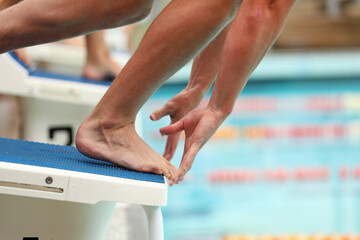 A close up view of a swimmers feet and hands on the starting blocks at the exact moment of starting...