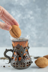 Female hand dipping a sweet walnut shaped cookie in cup of tea