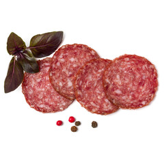 Slices of salami isolated over white background closeup. Sausage and basil leaves top view..