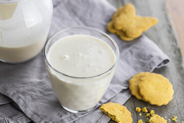 Selective focus to top view of glass with fermented baked milk and some blurred biscuit on the old wooden table.