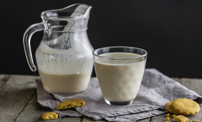 Selective focus to glass with fermented baked milk and blurred jug in background on the old wooden...