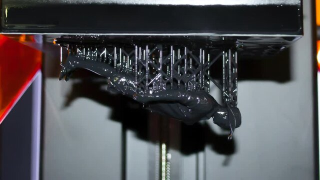 Stereolithography DPL 3d printer create detail and liquid drips, platform slowly move with liquid close-up. Progressive modern additive technology 3D printing, create scaled model by UV polymerization
