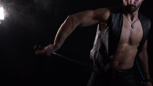 Muscular Man playing with long sword isolated on black background