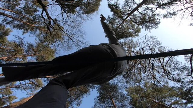 Man jumping and doing tricks on slackline in the forest in slow motion 