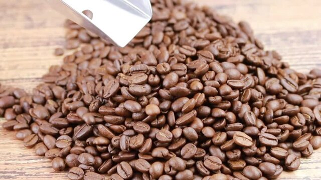 pelle en fer versant des grains de caf&eacute; sur une table