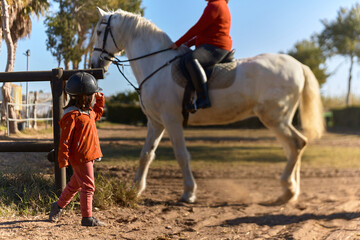 4-year-old girl on horseback greeting her mother who is riding a horse