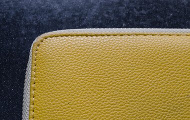 Detail of yellow leather wallet or briefcase with stitching on gray background.