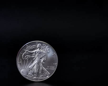An American silver eagle coin on a black backdrop