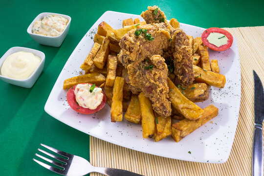 Plato de comida hecho de chicharrón de pollo, frito, broaster con papas fritas en plato blanco para restaurante en fondo verde