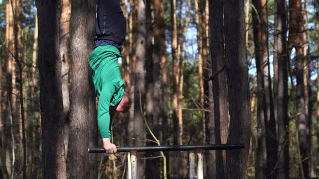 Man working out on the parallel bars in the forest. Healthy lifestyle