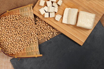 Soyabeans curd tofu soya beans flowing bamboo sieve wooden board on jute black stone slate background