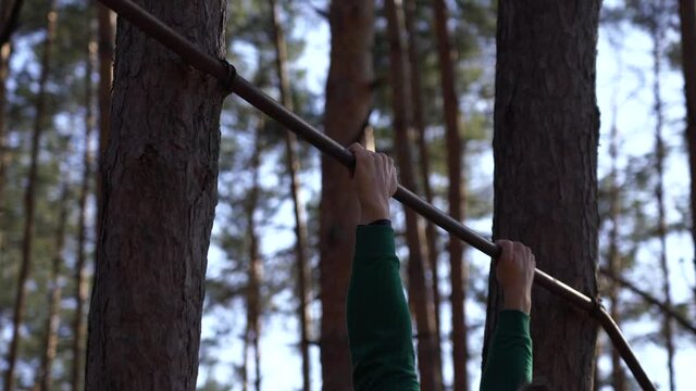 Man working out on the horizontal bar in the forest. Healthy lifestyle