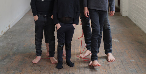 Family look bare feet wearing black outfit on wooden floor. Legs shot, closeup, modern fashion...