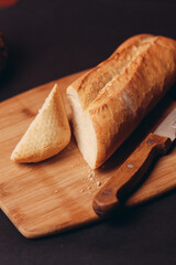 a loaf of bread sliced on a board and pastries baked goods dark background
