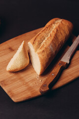 a loaf of bread sliced on a board and pastries baked goods dark background