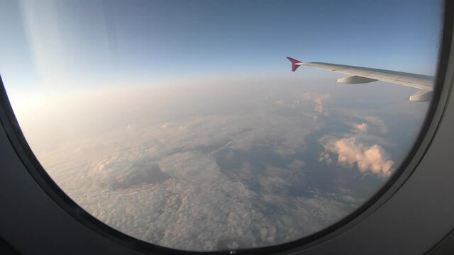 Timelapse from the plane's window flying above the beautiful clouds. Concept of travel and journey 