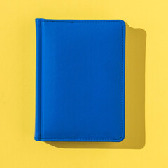 A blue notebook in bright light on a yellow background.