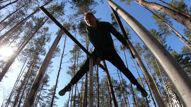 Man doing gymnastic on the parallel bars in the forest. Healthy lifestyle