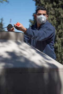 Hombre con mascarilla KN95 da mantenimiento a su suministro de agua durante pandemia