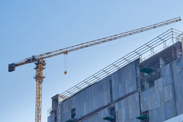 Construction site with the crane on sky background. Big yellow machinery construction crane tool of building industry for heavy lifting. Business engineering equipment modern