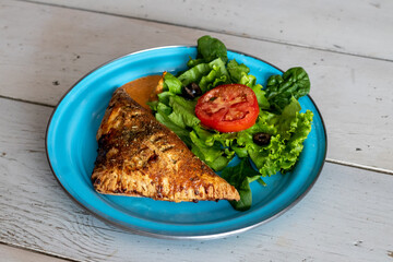 Cheese and ham wrap with salad on a blue plate