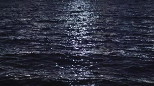 Ocean waves going back and forth at night, illuminated by moonlight