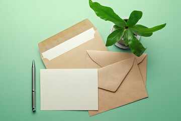 Brown envelope with blank card and pen isolated on green background. Top view