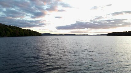 Cinematic drone flying over water in the Adirondacks flying over canoe