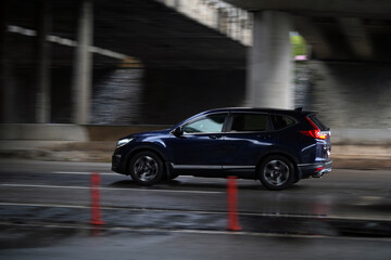 Shah Alam Selangor, Malaysia - February 18, 2021: Selective focus on panning shot of Blue black Honda CRV cruising on slippery road.