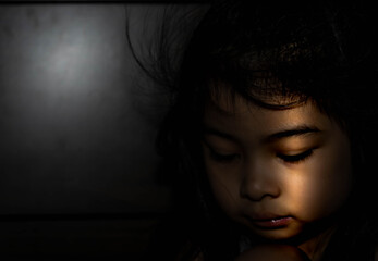 Powerful shot of a sad asian child. Female asian child sad dark scene