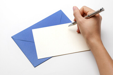 Woman’s hands writing with pen over blank paper card and envelope isolated on white background. 