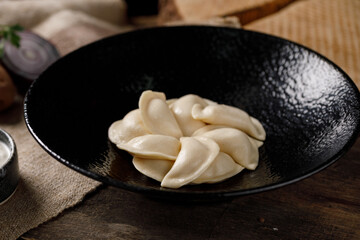 Appetizing traditional Russian dumplings, hand-made with potatoes. Still life on a wooden board. Close-up.