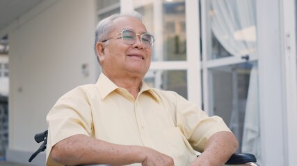 Disabled senior man sitting on wheelchair alone in rehabilitation center, Portrait happy Asian...