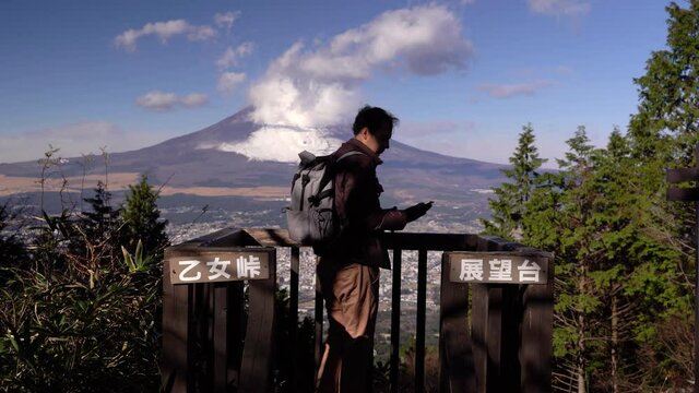Male hiker taking selfies at viewpoint with backdrop of Mount Fuji