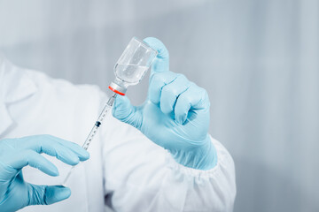 Doctor or scientist wearing antivirus clothing In the laboratory, research laboratories are studying and developing a medical vaccine, COVID-19, holding a syringe with a liquid vaccine.