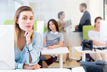Fototapeta premium Portrait of frustrated young unhappy business woman in coworking space with working colleagues behind