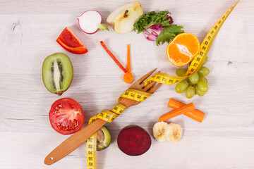 Fototapeta na wymiar Tape measue with fruits and vegetables in shape of clock showing time to healthy eating and slimming