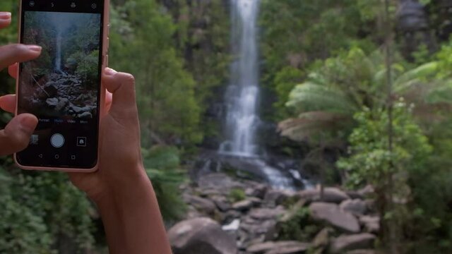 Taking photos on phone at an instagrammable waterfall Erskine Falls