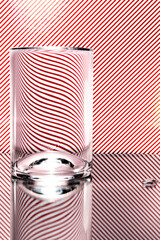 refraction of light by a wine glass on a red and white striped background. Abstract glass art.