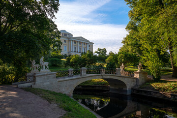 Fototapeta na wymiar Centaur Bridge in Pavlovsky Park against the background of the Pavlovsky Palace on a sunny summer day, garden and park reserve in St. Petersburg, Russia